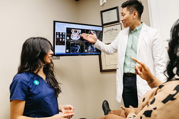 Jacksonville University Implantology resident discussing procedural options with a patient and a female chair-side assistant