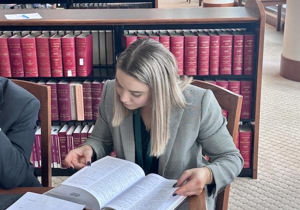 A female student sitting at a desk, reading a book.