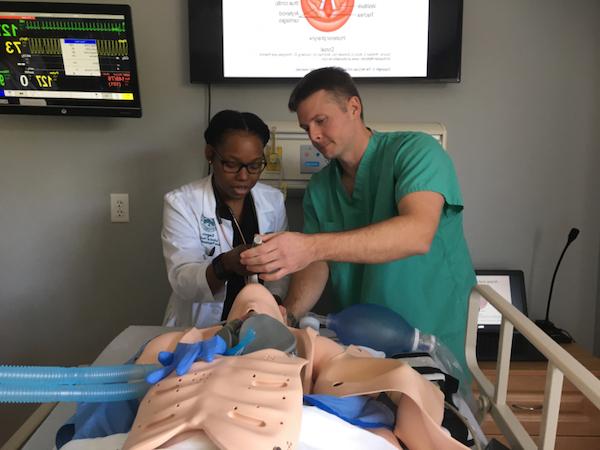 Nursing students testing intubation methods using a medical mannequin.